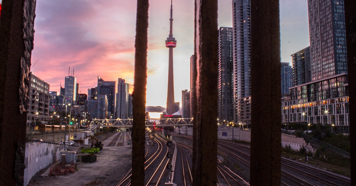 Has Canada started allowing TRV Applications for Visit Visas? - Through railing bars scenery of evening Toronto city with contemporary glass skyscrapers at sundown