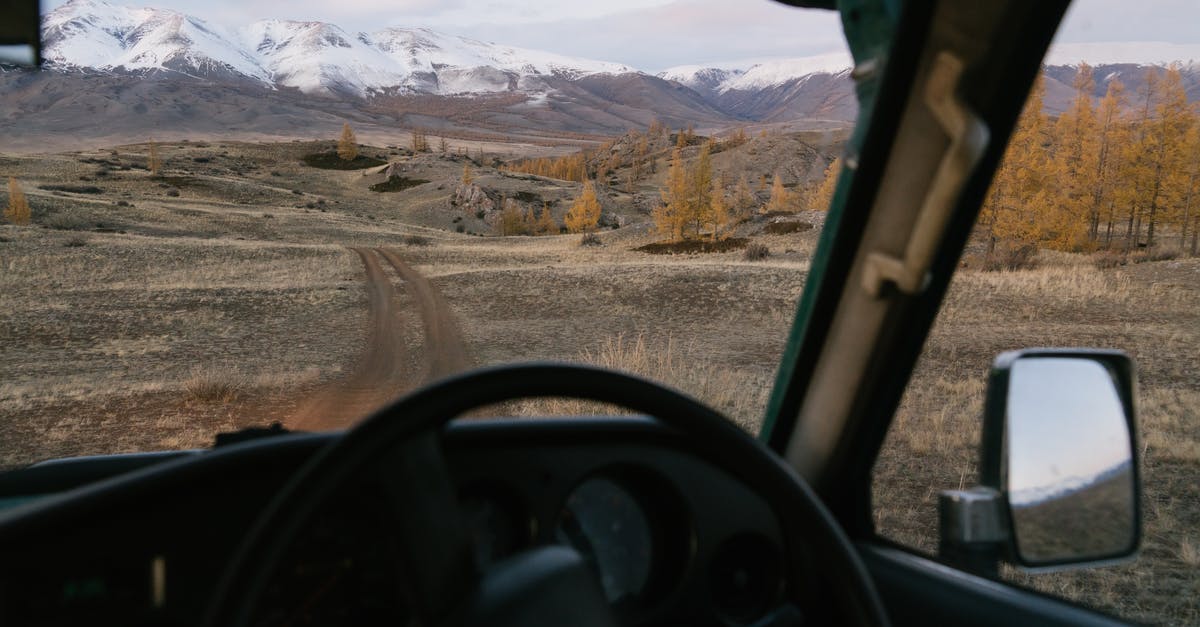 Hazards on road trip through Italian Alps - Empty road going through prairie to mountains viewed from car in countryside travel through Mongolia