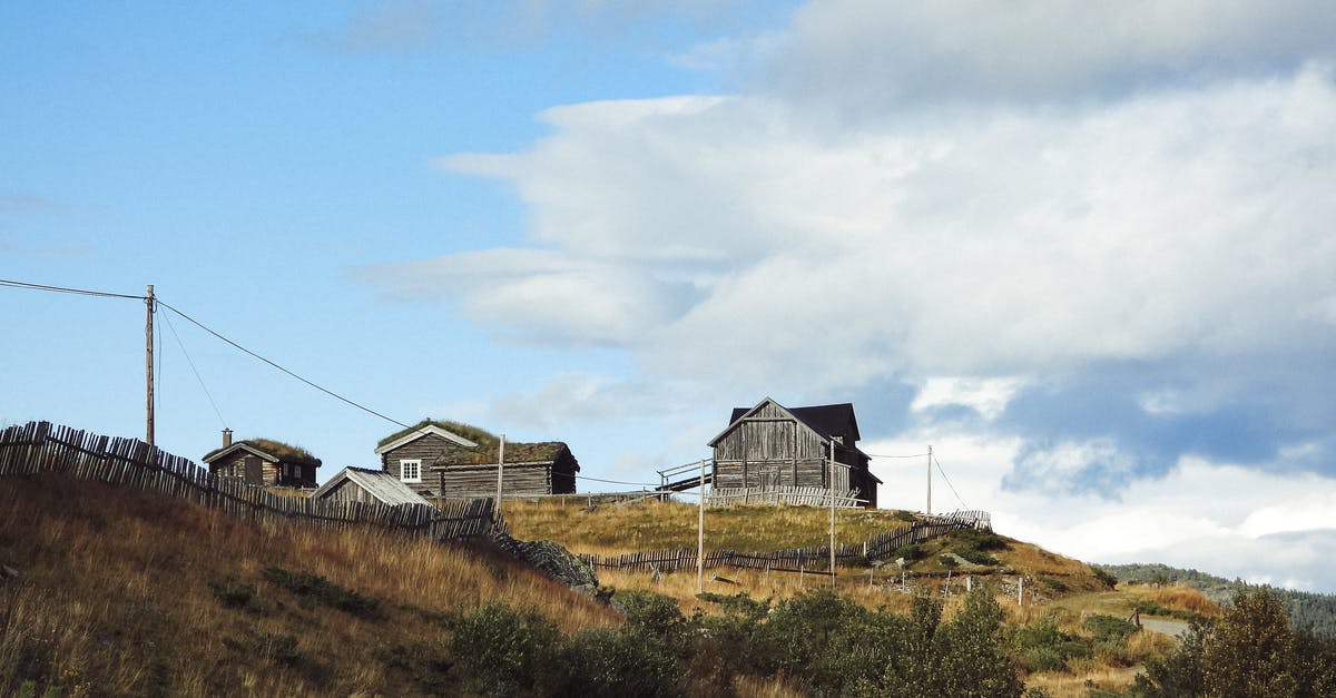 Health-care out of our country - Aged residential wooden buildings with fence located among dry grass and plants in village