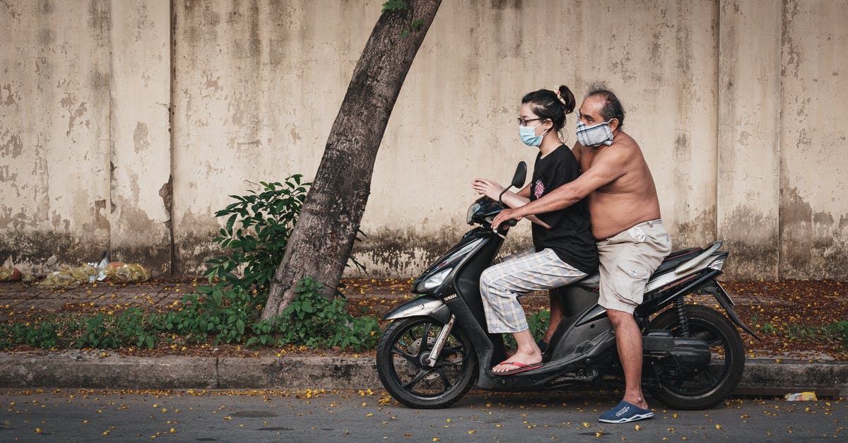 Hearing protection on the road in China - Man and Woman Sitting on Black Motorcycle