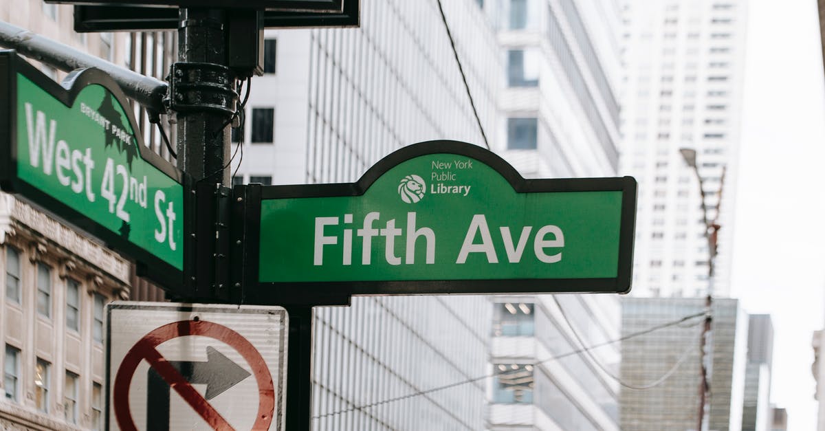 Highest point in NYC that may be reached for free? - Metal post with direction indicator on avenue with high skyscrapers in New York