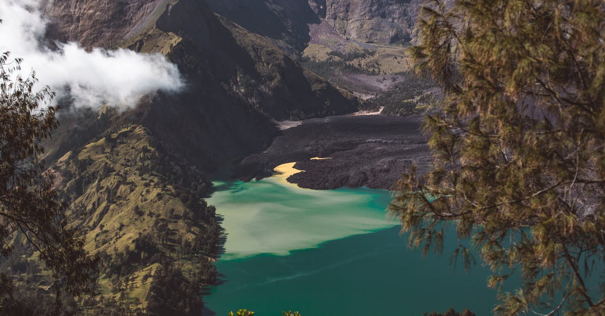 Hiking along Mount Aso volcano's caldera - Picturesque turquoise Segara Anak lake located in volcano caldera and surrounded by rocky hills