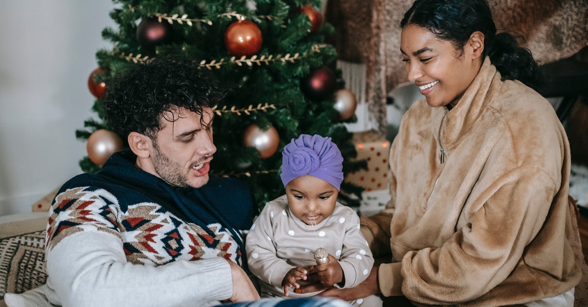 Hiking with children close to Prague, Czechia in winter - Happy parents having pleasant time with baby against Christmas tree