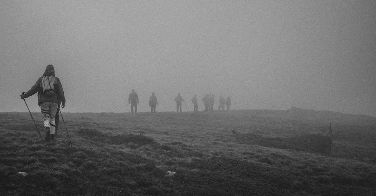 Hill walking and camping in the Peak District - Group of people with backpacks hiking in mountainous terrain covered with thick dense fog