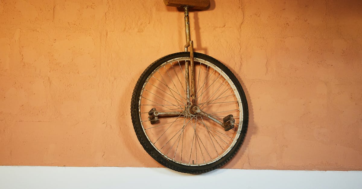 Hiring and buying used bicycle in Tbilisi, Georgia - Old shabby unicycle hanging on brick wall