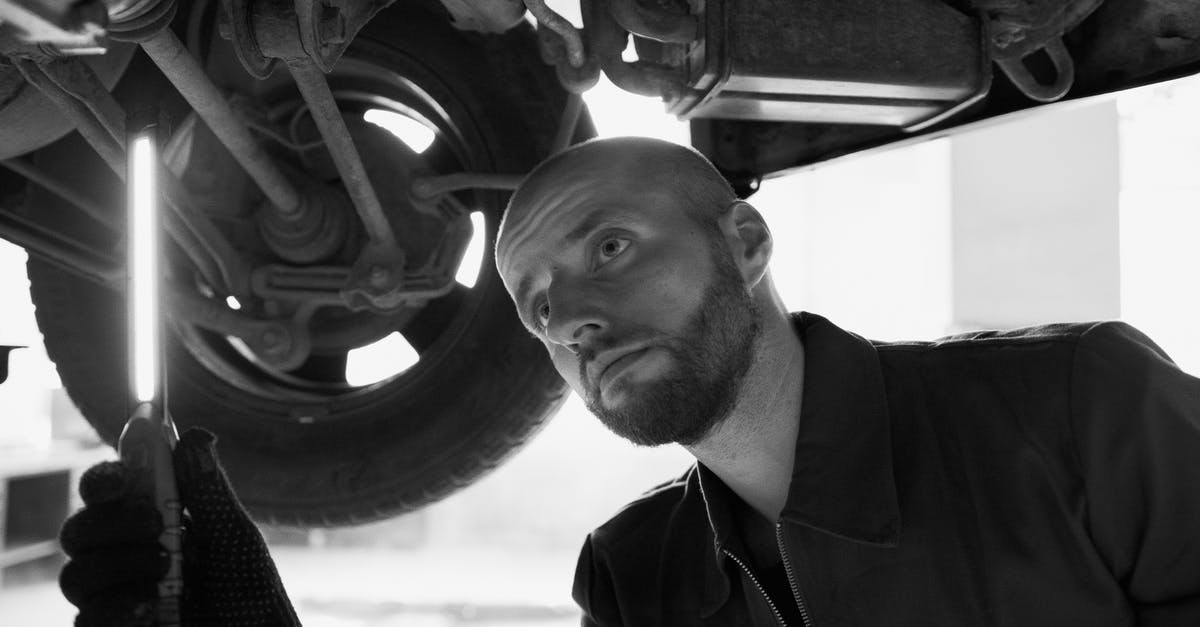 Hiring car in Florida under 21 y/o with European license? - Black and White Photo of a Mechanic Under a Car