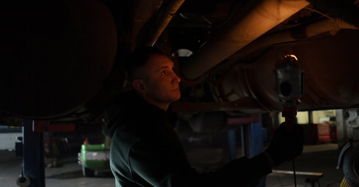 Hiring car in Florida under 21 y/o with European license? - A Man Holding a light Checking the Underbody of a Vehicle
