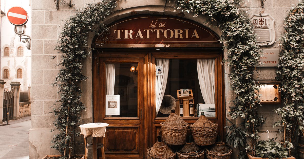 Hitchhiking in Europe under the age of 18 - Exterior of cozy Italian restaurant with wooden door and entrance decorated with plants