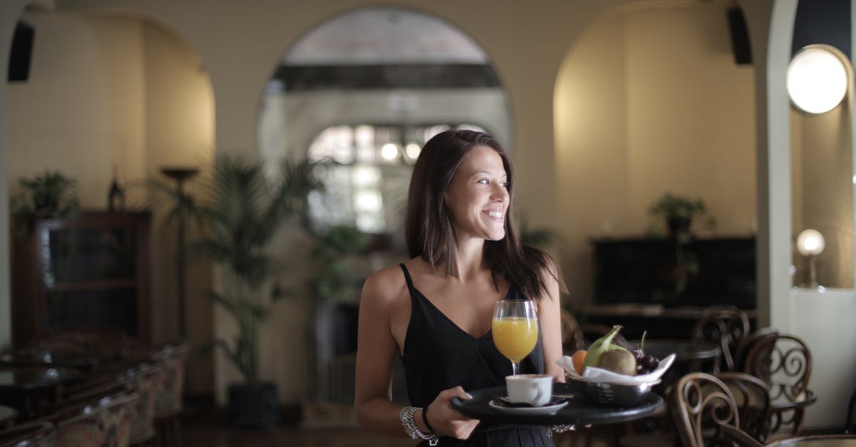 Hotel early arrival for another guest - Happy woman carrying tray with breakfast in hotel restaurant