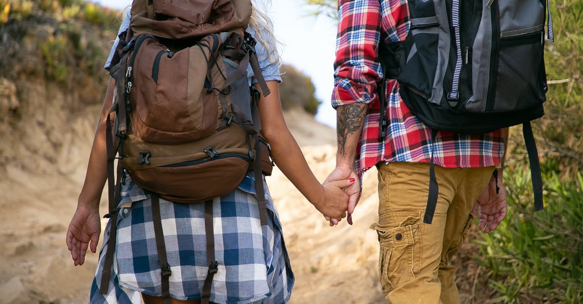 How are combined dimensions calculated for checked baggage on Ryanair? - Man and Woman Holding Hands While Walking on Brown Sand