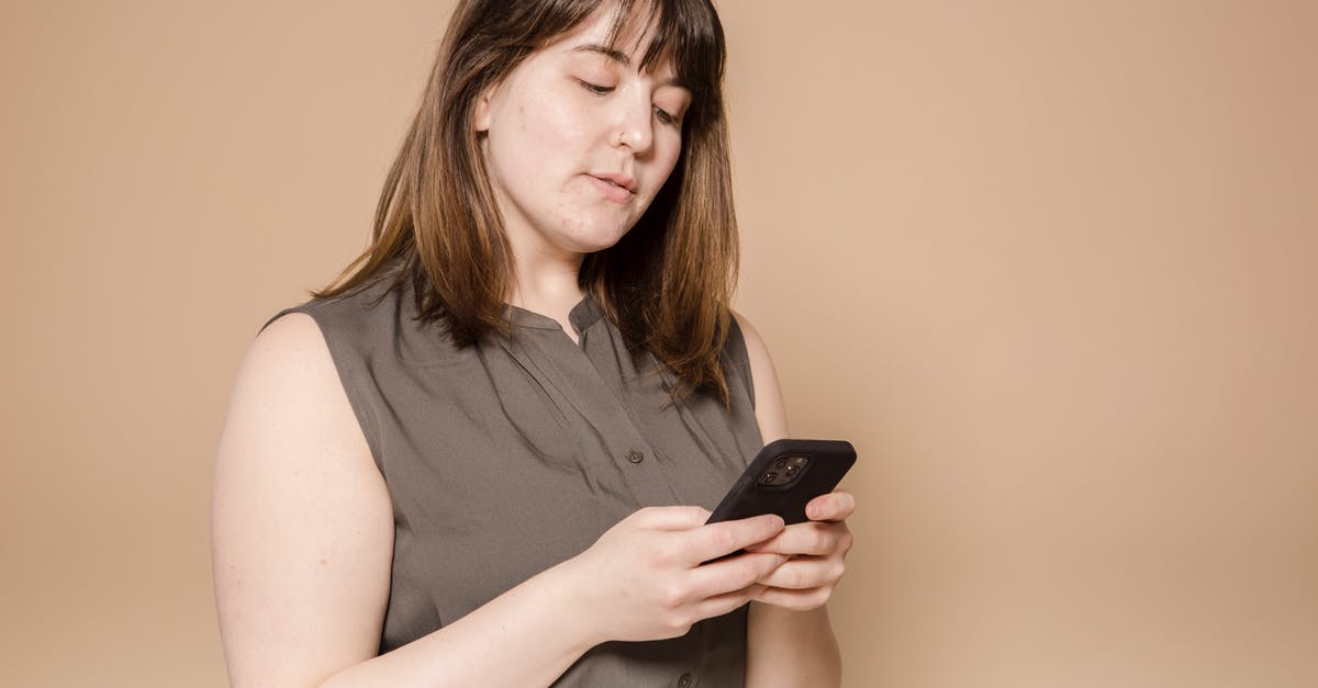 How are overweight surcharges calculated for connecting flights with Spirit? - Focused plump Asian female in stylish wear text messaging on modern cellphone while sitting on beige background in light studio