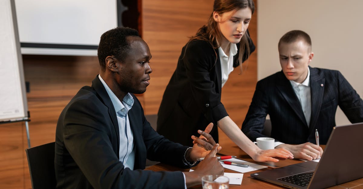 How available is Internet in Sierra Leone? - Man in Black Suit Jacket Sitting Beside Woman in Black Blazer