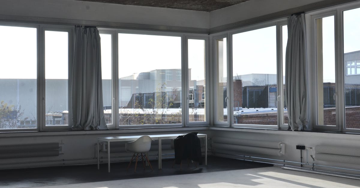 How big are Premier Inn Hub "Bigger" rooms? - Chairs placed at table near big window with curtain and modern cityscape view with buildings in minimalistic empty room in sunlight