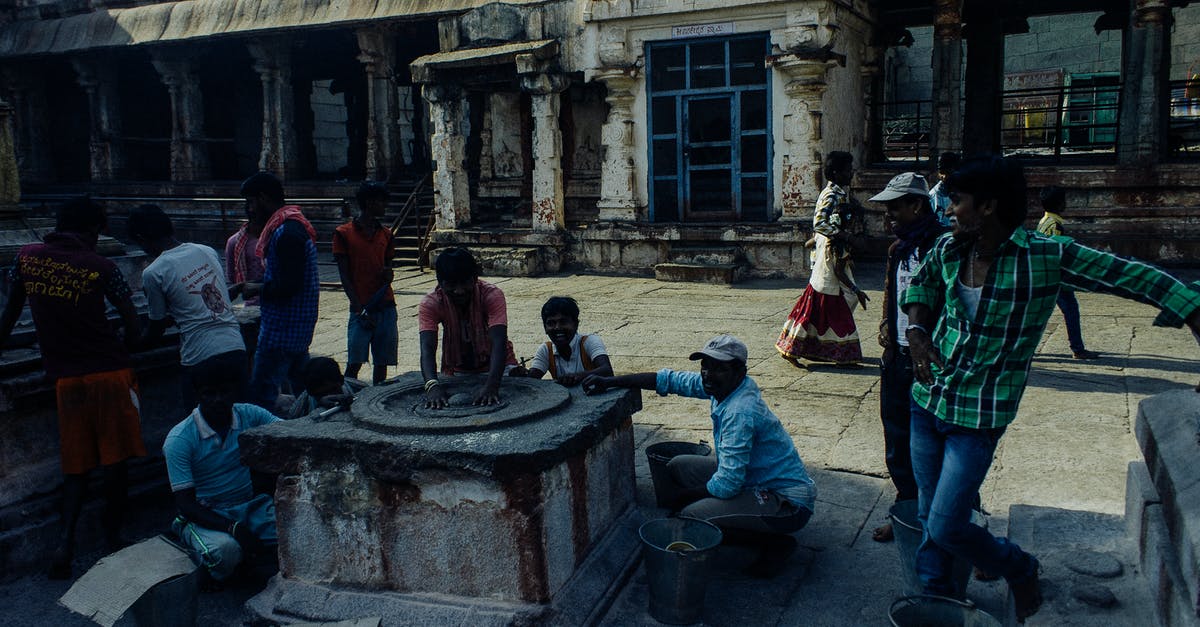 How can an Indian citizen travel to Trinidad and Tobago from India without needing a transit visa along the way? - Asian people in casual clothes standing near and touching weathered religious stone wheel located in center of medieval historic Hampi village in India