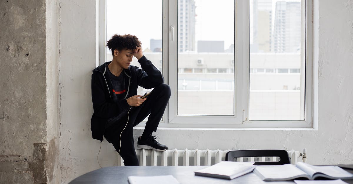 How can AT&T charge me to use WiFi while I'm abroad? - Tired African American male student surfing charging mobile phone during break in studies in loft style room