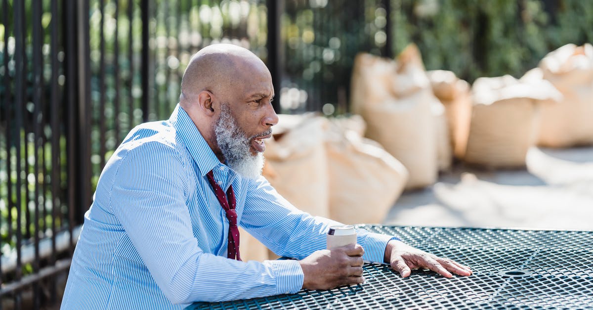 How can I address ECO's concerns about my employment? - Side view of concerned African American male entrepreneur in formal clothes with can of alcohol beverage sitting at table on street