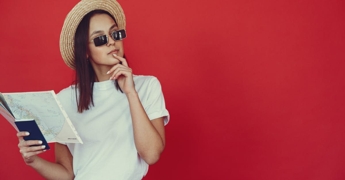 How can I check if tour services are reliable? - Thoughtful young woman in retro hat and trendy sunglasses holding map and touching chin while looking pensively away on red background