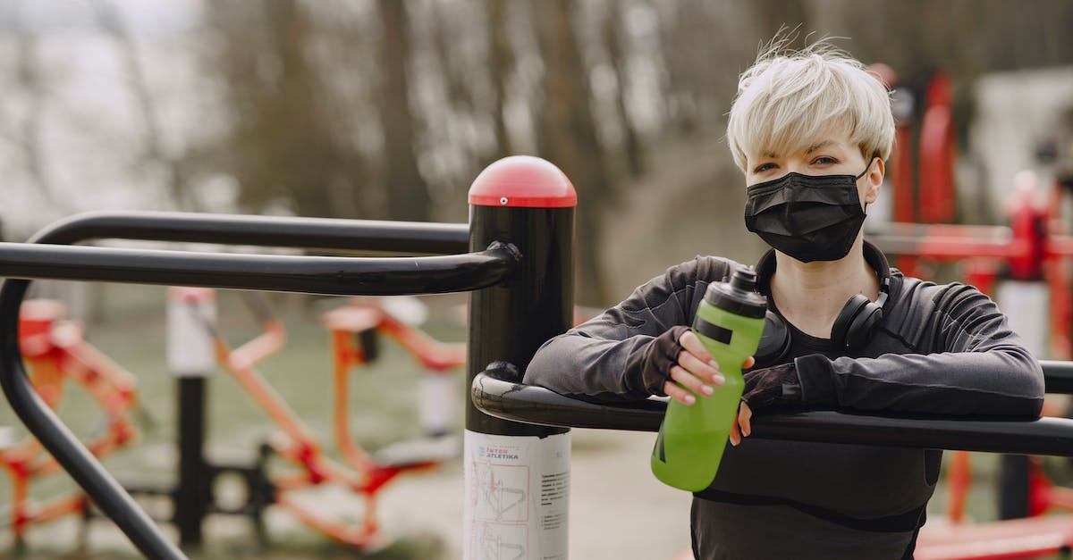 How can I determine which airlines are relatively safe? - Stylish woman in medical mask with bottle of water on sports ground in street