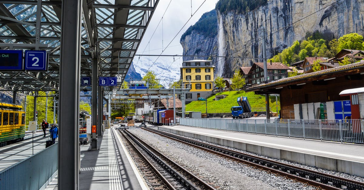 How can I find my train platform number at Zurich? - Railroads near station and rough mountains under sky