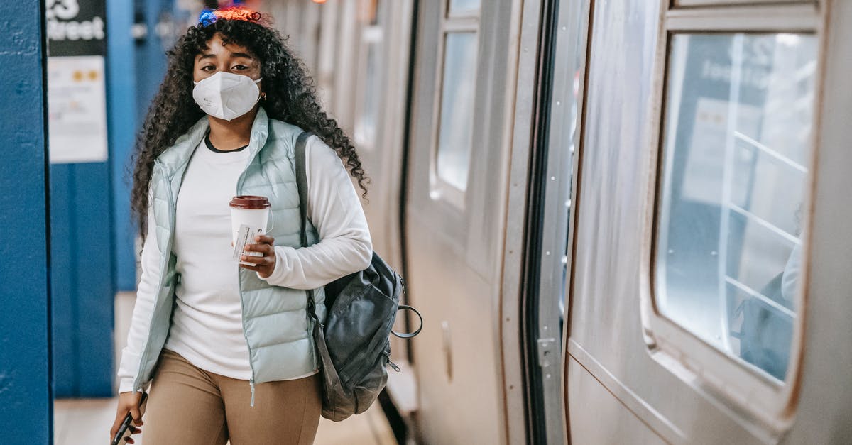 How can I go to Perperikon by public transport? - Calm black woman with coffee wearing medical mask standing in metro