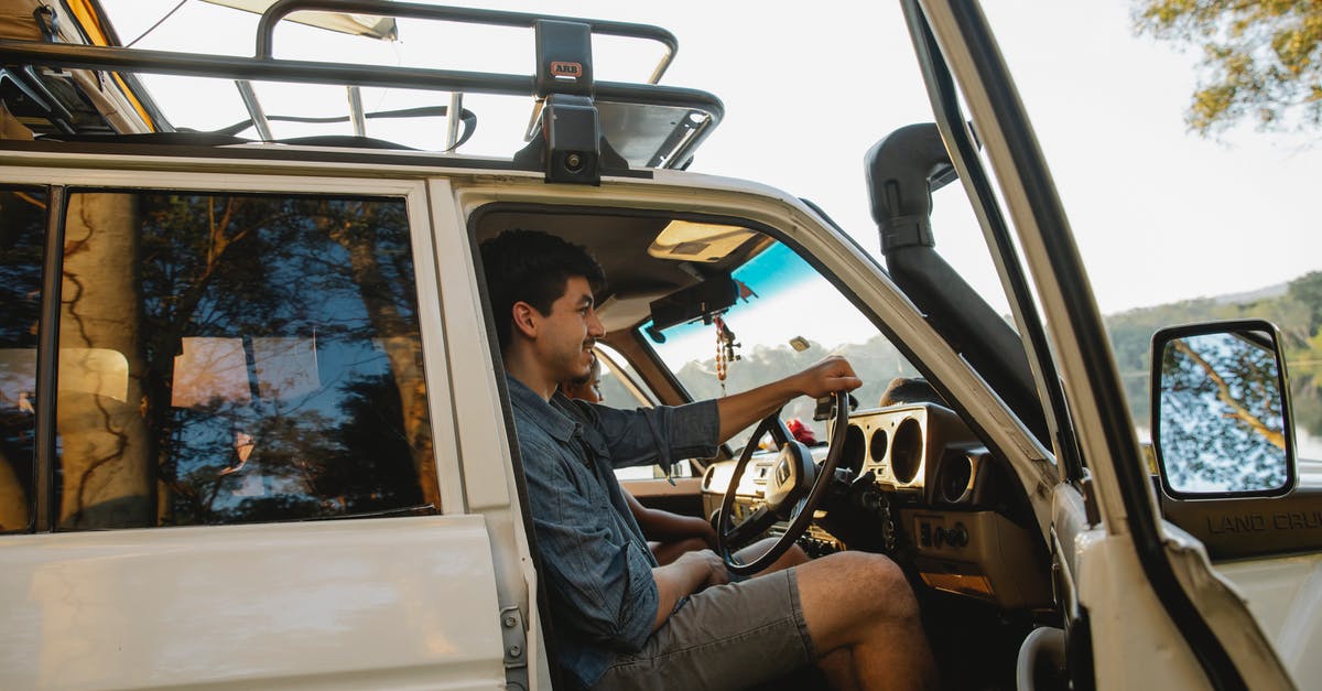 (How) Can I hire an instructor as a tourist driver on the Nürburgring without renting a car? - Side view of cheerful young male traveler in casual clothes smiling while driving SUV car with tent on roof during road trip in nature (How) Can I hire an instructor as a tourist driver on the Nürburgring without renting a car? - Side view of cheerful young male traveler in casual clothes smiling while driving SUV car with tent on roof during road trip in nature