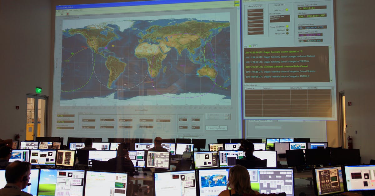 How can I manage online a booking for a Malaysian Airlines flight issued by British Airways? - Back view of unrecognizable employees working on computers in flight control room with big interactive map on wall and analyzing data
