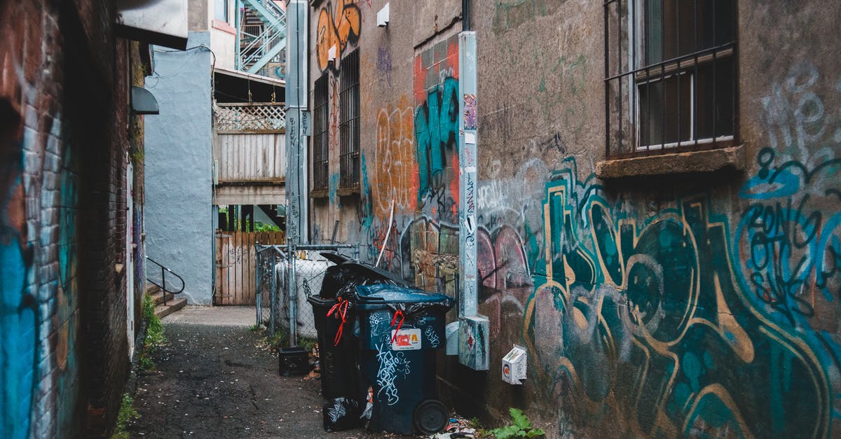 How can I proceed regarding a possibly-lost letter when travelling? - Garbage can on narrow street between aged houses with graffiti on shabby walls in town