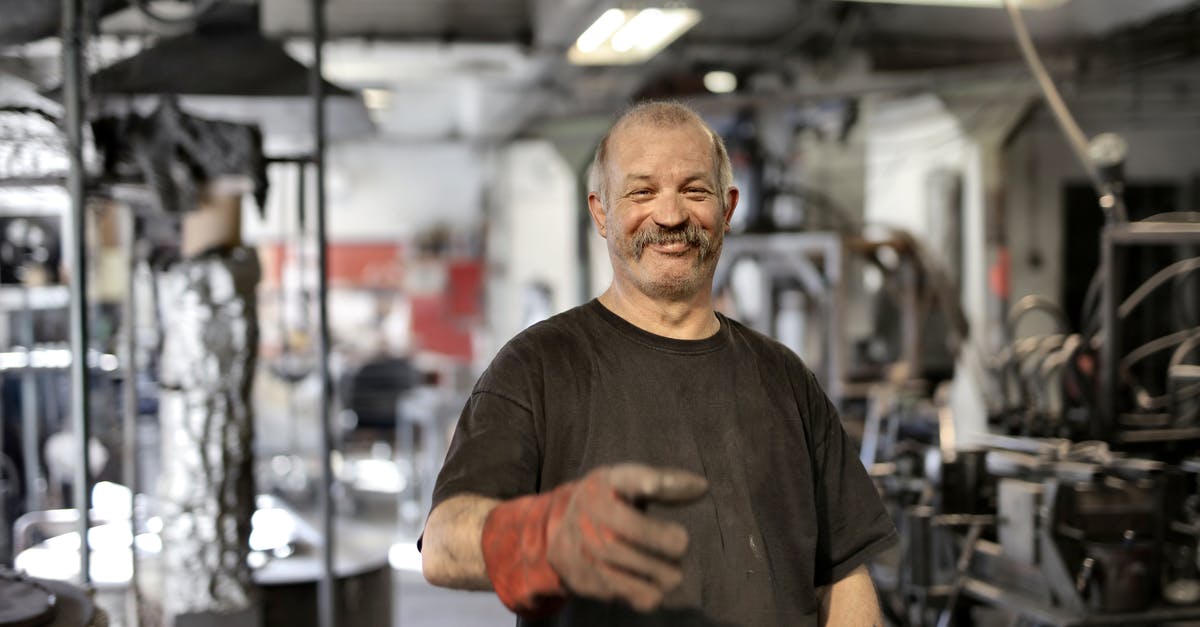 How can I repair my old and expired passport? - Cheerful senior white hair craftsman in heavy duty gloves laughing in workshop while looking at camera