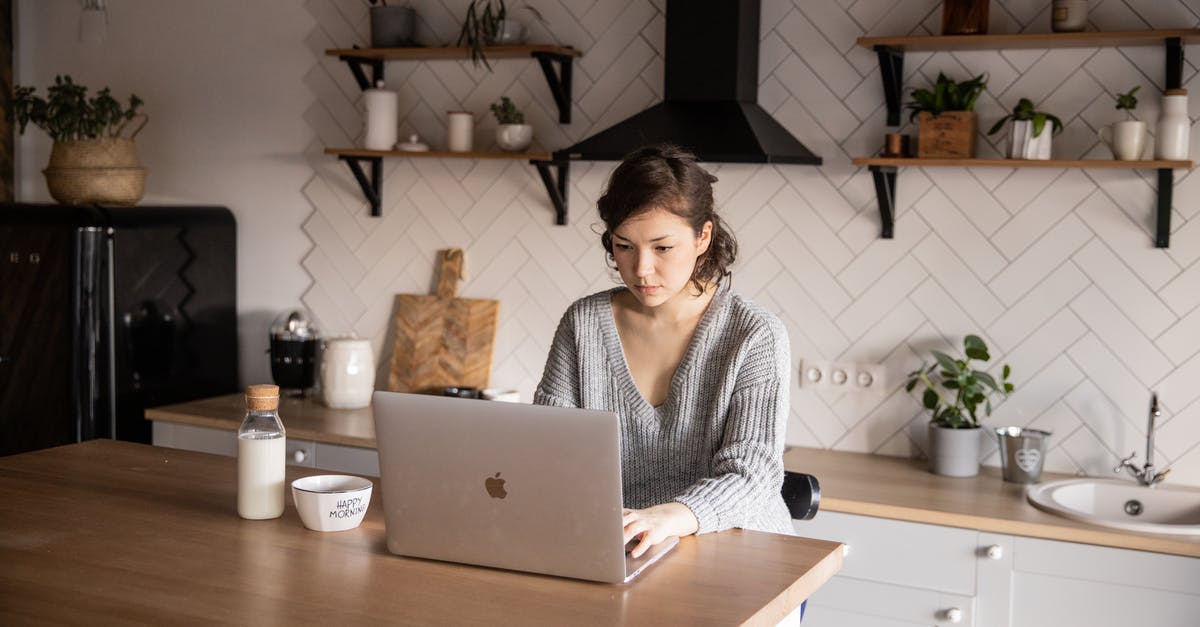 How can I search for hotels with kitchen(ette)s? - Content young woman browsing laptop in modern kitchen