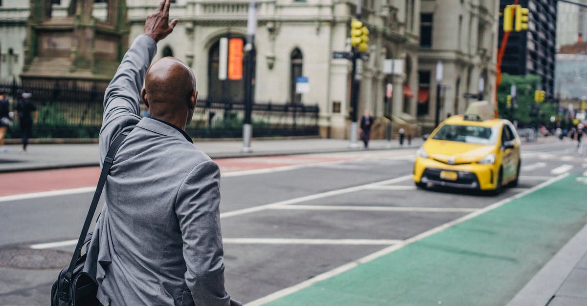How difficult is it to catch a taxi in Napa, California? - Back view of anonymous African American male with hand up catching yellow cab on blurred background of road