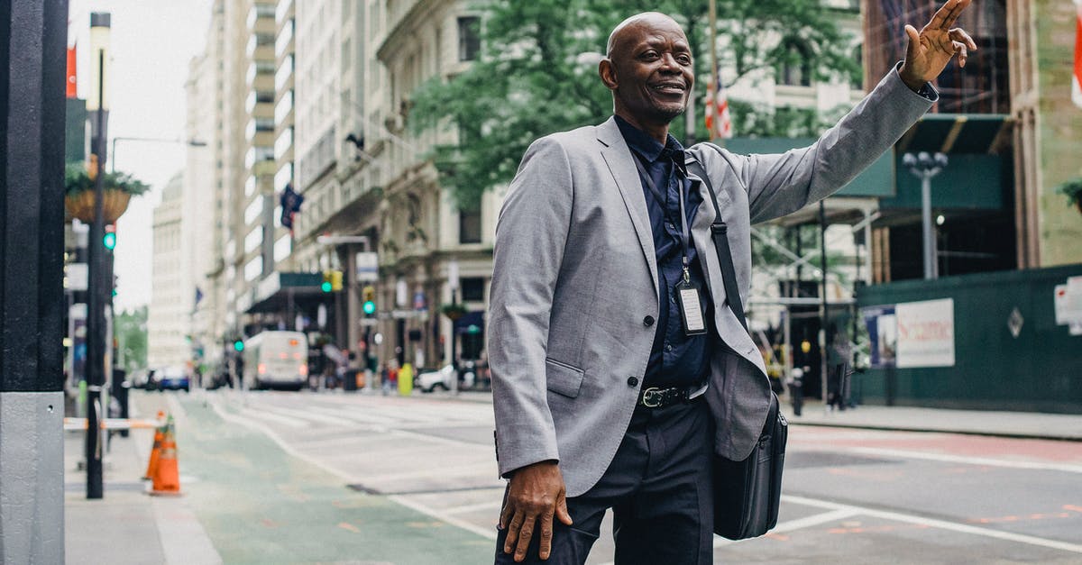 How difficult is it to catch a taxi in Napa, California? - Cheerful successful African American entrepreneur waiting for taxi on local street of modern city
