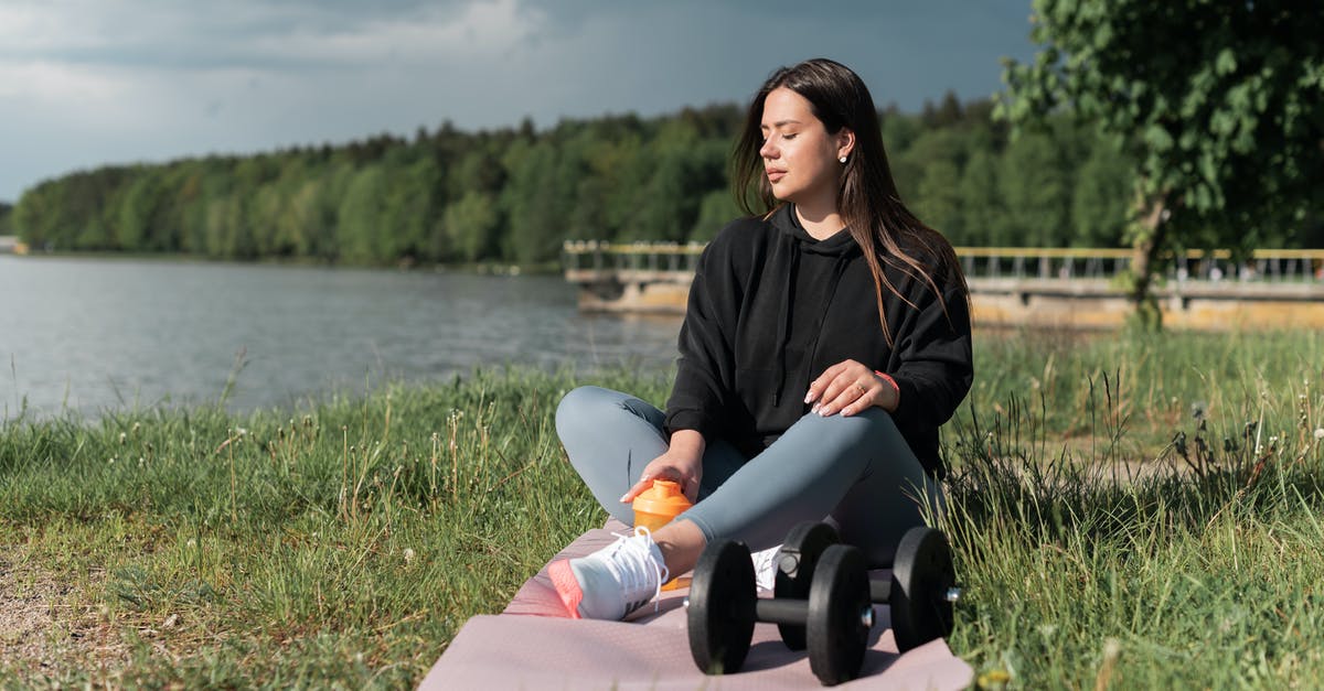 How do airlines compute weight allowances for carry-on bags? - Woman in Black Jacket Sitting on Pink Textile Near Body of Water