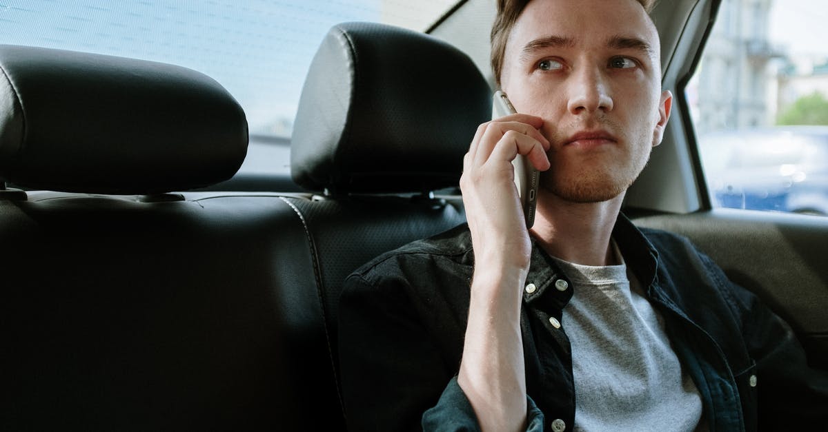 How do I book a taxi ride in Spain? - Man in Gray Button Up Shirt Sitting on Black Leather Car Seat