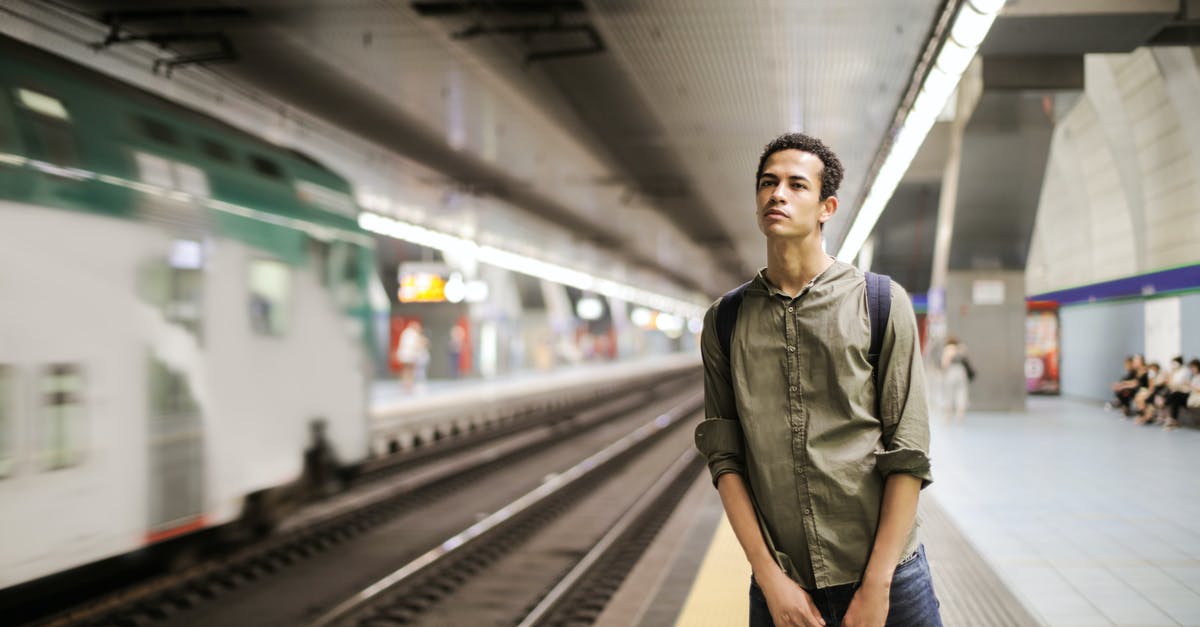 How do I carry parrots on an Indian Railway train? - Photo of Man in a Green Shirt Standing Alone on Train Station Platform