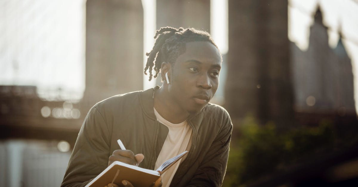 How do I create all-inclusive travel packages for a wedding? - Pensive black man drawing picture in notebook while standing on riverbank