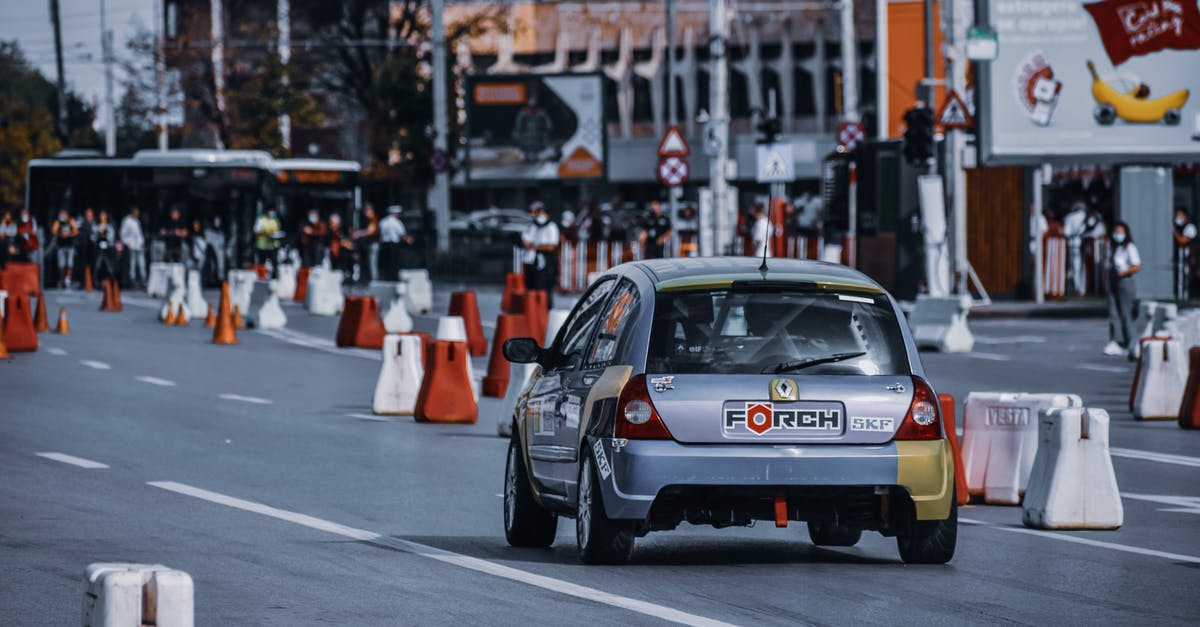 How do I get to Alpe d'Huez by public transportation on the race day? - Modern silver car driving on street with traffic cones