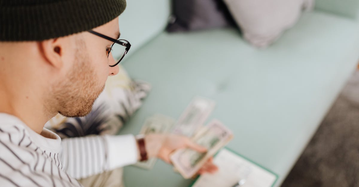 How do I keep my cash safe in Japan? - Man in Black Beanie Hat Holding Money 