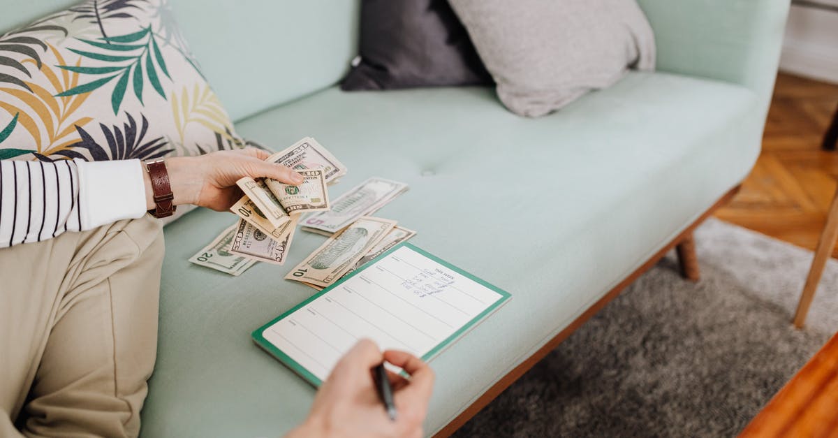 How do I keep my cash safe in Japan? - Person Writing on Paper While Counting His Money