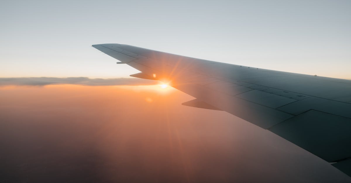 How do I redeem airline vouchers when booking through a website? - Wing of airplane flying against sunset