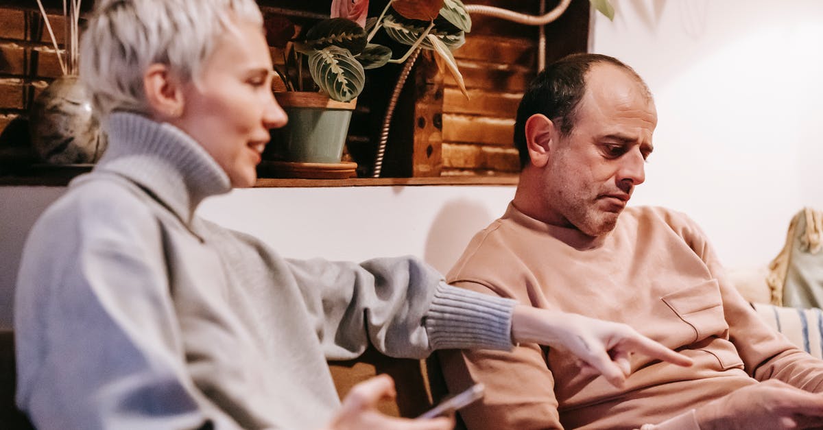 How do I search for connecting point-to-point flights? - Middle aged multiethnic spouses using gadgets on sofa at home