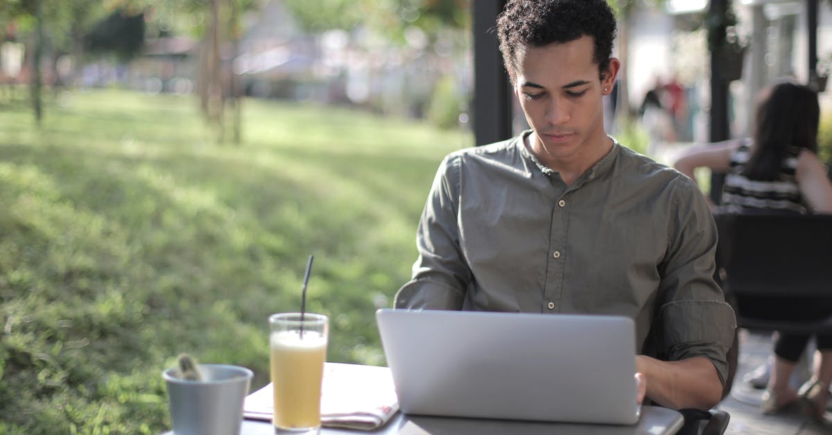 How do I search for upscale self-service restaurants? - Focused black male freelancer using laptop in street cafe