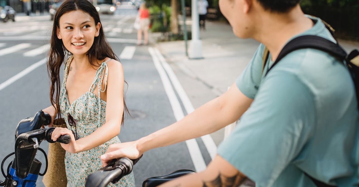 How do US intercity bus companies relate to each other? - Smiling couple in casual clothes standing with bicycles on asphalt road in city in sunny day