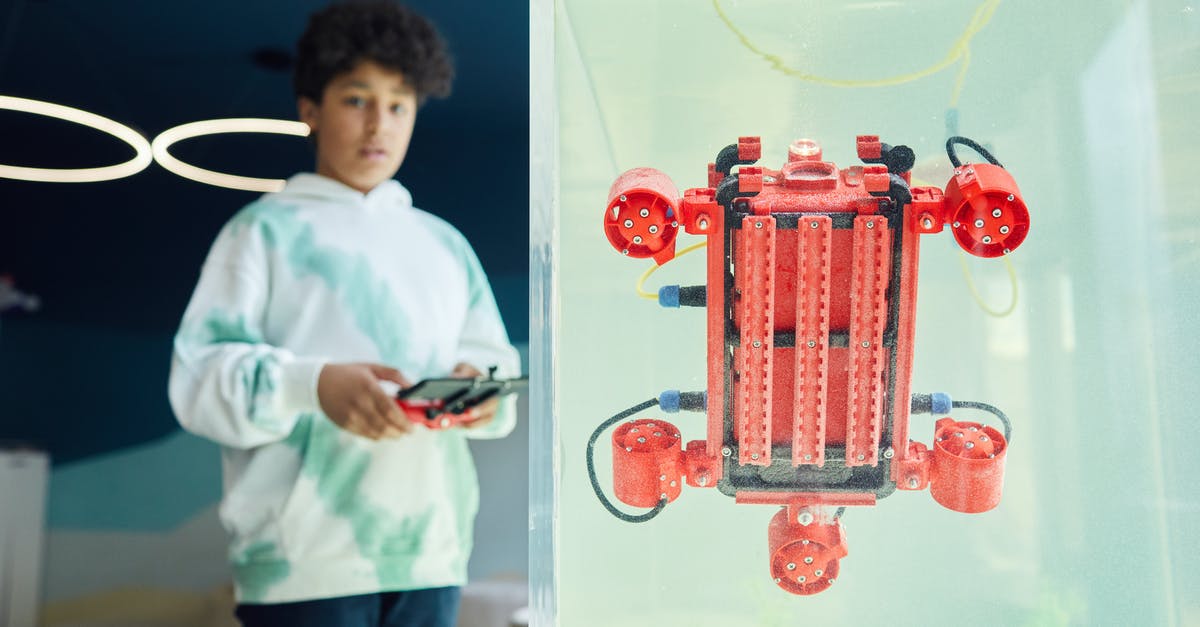 How do we connect in Cyprus to our flight with Emirates? - From below of ethnic boy in hoodie controlling robot using panel while standing in light room