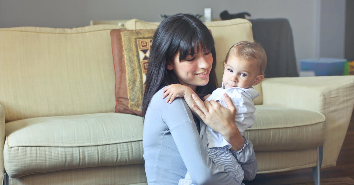 How do you seat a baby securely on a coach transfer? - Woman in Gray Sweater Carrying Toddler in White Button-up Shirt