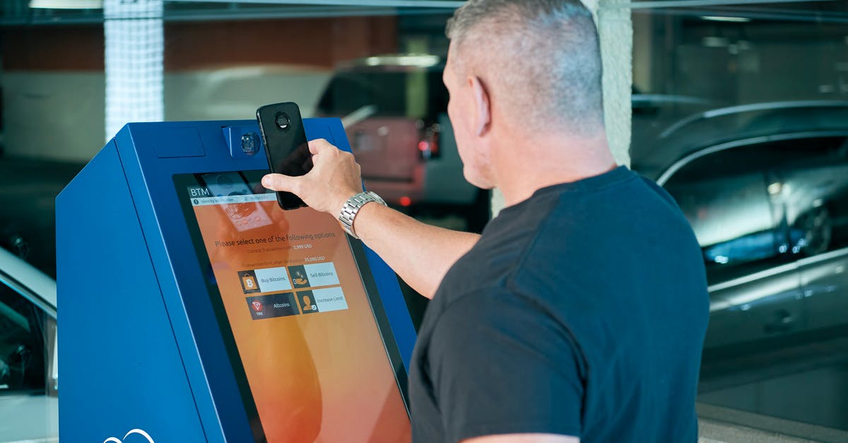 How do you use ATM machines abroad? [closed] - Man Placing his Phone on an ATM