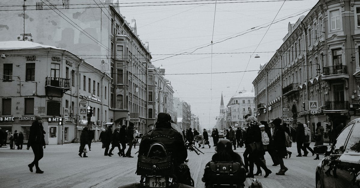 How do you use Berlin crosswalk signal boxes? - Black and white of people crossing asphalt road while cars and motorcycle with sidecar waiting for permission signal of traffic light in city in daylight