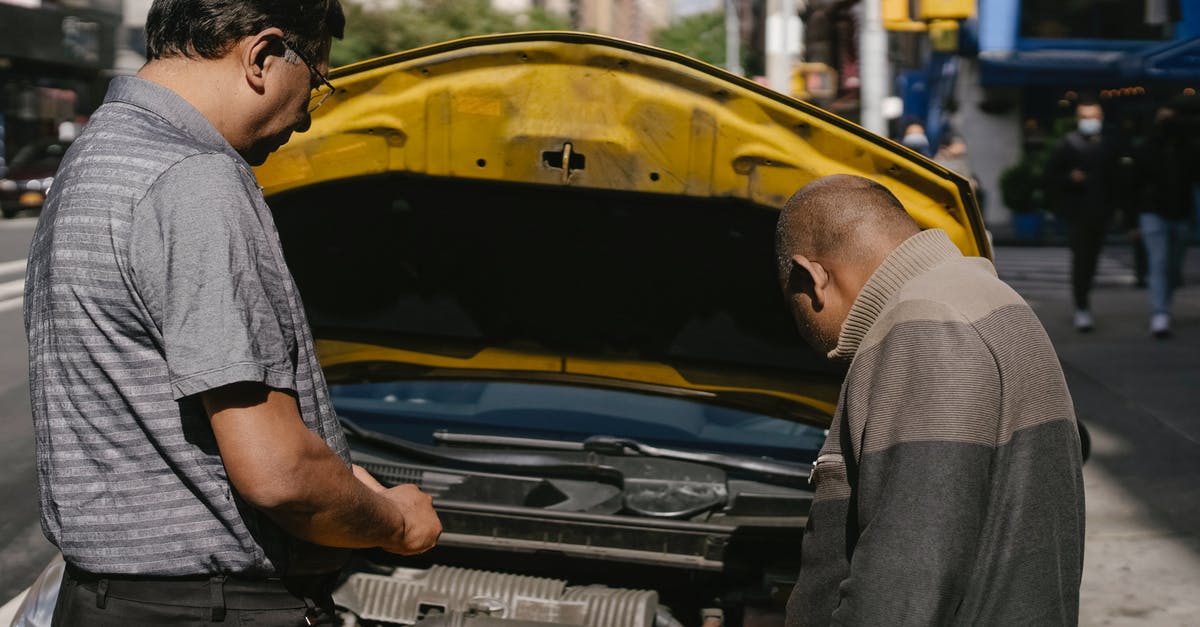 How does Caltrain check whether cars parked at Caltrain stations belong to Caltrain customers? - Ethnic mechanic checking car standing near man
