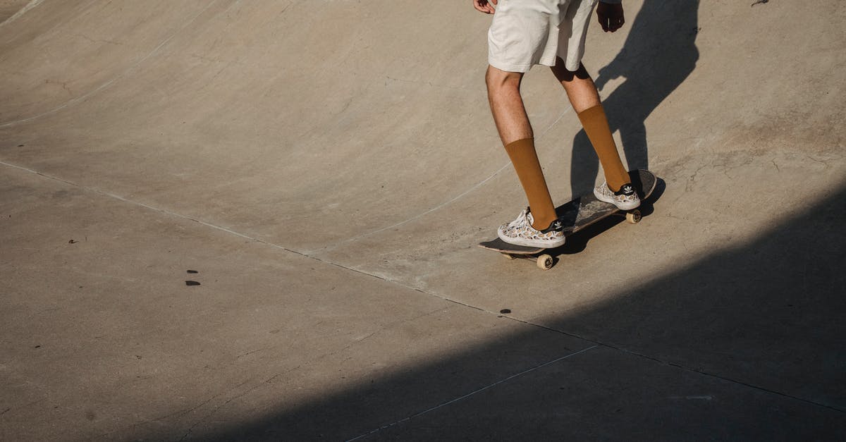 How does jetBlue determine its boarding order? - Crop anonymous male skater wearing white shorts riding skateboard on asphalt ramp in skate park on summer sunny day