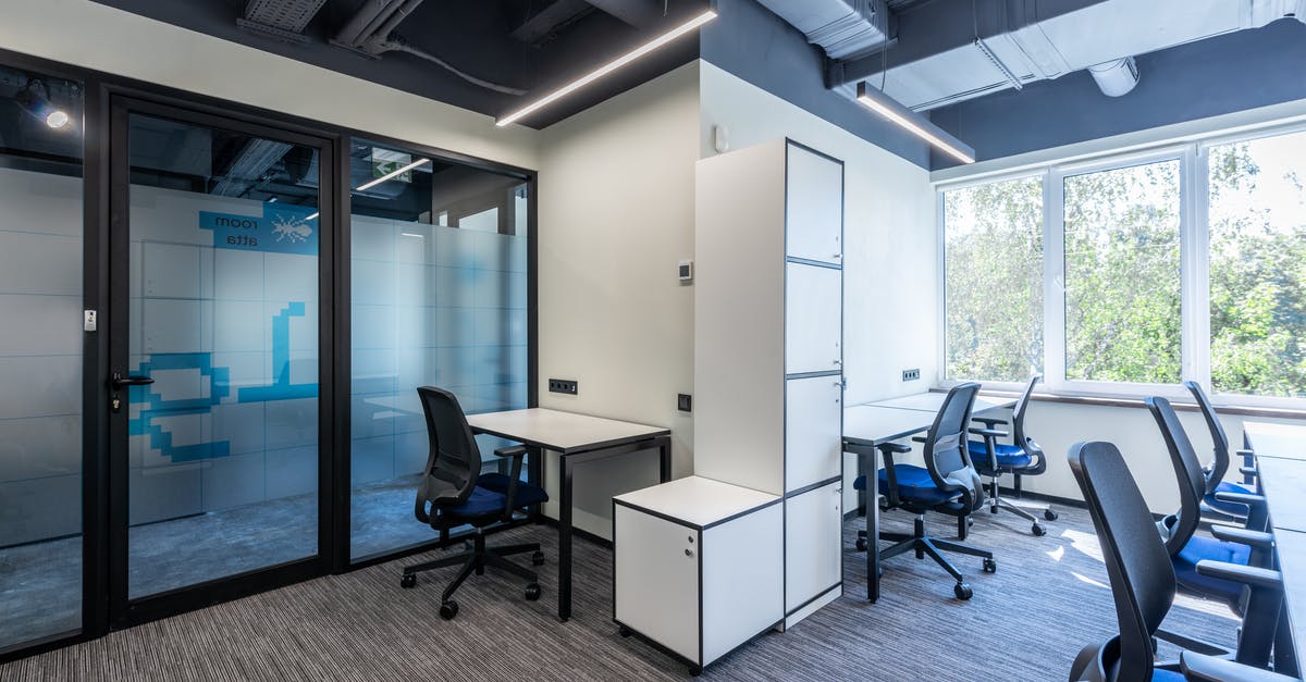 How does Schengen multiple entry visa work? - Desks with armchairs placed in spacious open space office with glass doors and white cupboards near big window in business center