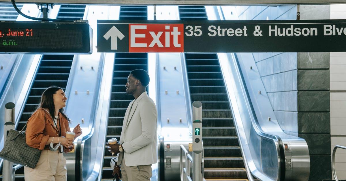 How does the train ticket pickup system work in practice? - Man in White Dress Shirt and Blue Denim Jeans Standing on Escalator